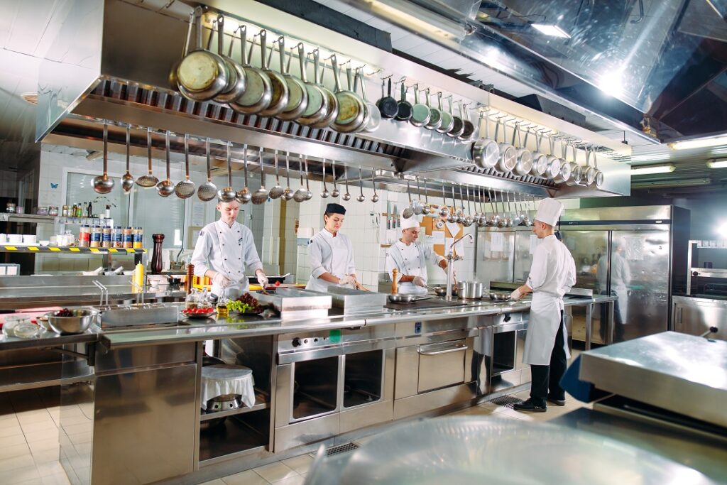 commercial kitchen with white uniform staff pans above